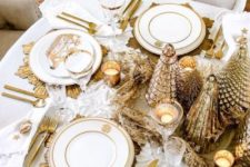 16 a super glam gold and white Christmas table with a shiny centerpiece, candles, sunburst placemats, cutlery and gold rim glasses