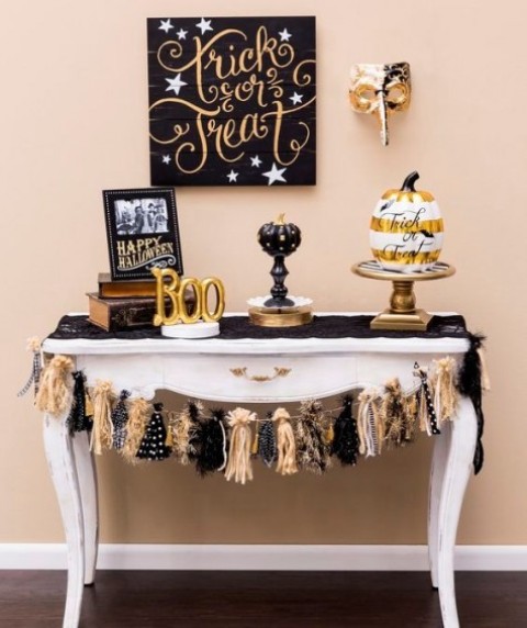a glam dessert table in black and gold, with letters, pumpkins, a garland and a sign   just add treats and voila