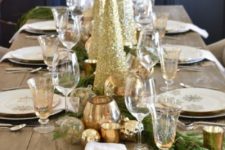 17 a stylish Christmas table with evergreens, gold snowflakes, placemats, gold glitter cone trees and gold ornaments and candleholders