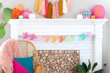 18 a super colorful Halloween mantel and fireplace with a bright ghost garland, a tassel artwork and colorful pumpkins