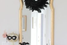 23 a mirror in a gilded frame, a blakc feather wreath, black bats and spiders, white and pink pumpkins plus a pumpkin in a mask