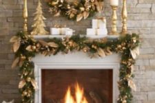 23 a stylish fireplace with a gold wreath of fruit and leaves, a matching garland over the fireplace and gold candleholders