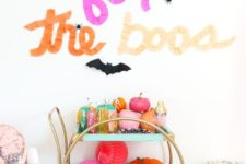 24 a super bright bar cart filled with colorful pumpkins and paper balls, colorful barware and with letters above