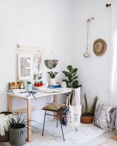 a boho chic home office nook with a white desk, macrame artworks, potted plants and signs