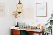 a cozy boho home office nook with a catchy Moroccan lamp, a potted plant, a mid-century modern desk, a boho rug and a green chair