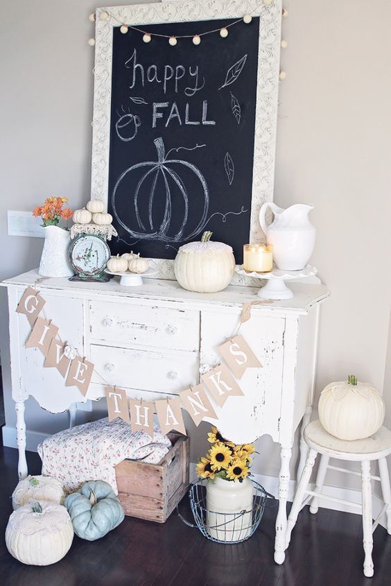 a cozy white console table with a burlap runner, white pumpkins, candles, a chalkboard sign and some neutral pumpkins on the floor