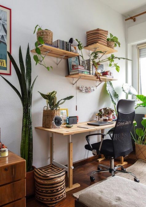 a small boho home office with a simple wooden desk, floating shelves, potted succulents and plants, baskets