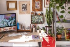 a small yet cozy boho home office with a cool gallery wall, a bright rug and a red chest, los of greenery and cacti