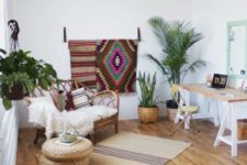 a welcoming boho space with a trestle desk, colroful rugs, potted plants, rattan and jute furniture