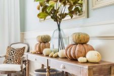 simple and natural Thanksgiving styling with real pumpkins, a foliage arrangement in a clear vase and chevron baskets