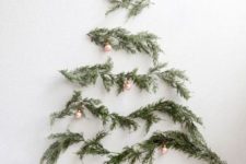 05 evergreen tree branches on the wall form a Christmas tree that is decorated with rose gold ornaments
