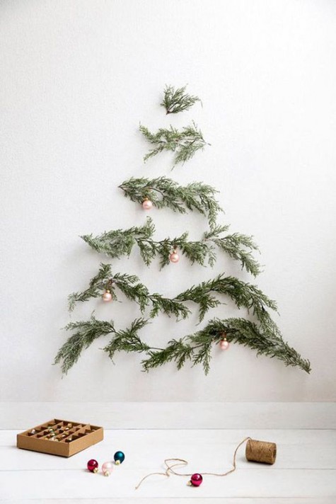 evergreen tree branches on the wall form a Christmas tree that is decorated with rose gold ornaments