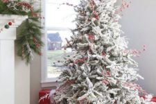 07 a flocked Christmas tree decorated only with lights and red berries and red and white gift boxes under it