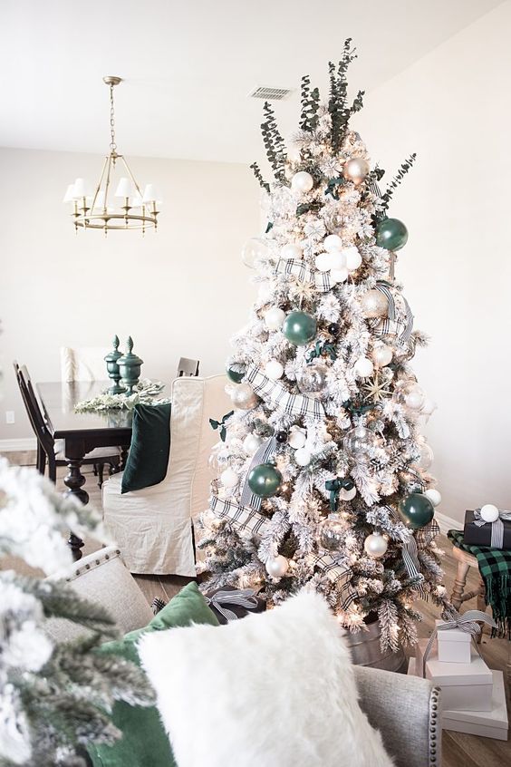a flocked Christmas tree decorated with green, pearly and sheer glass ornaments plus plaid ribbons and eucalyptus