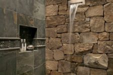 10 a natural shower space with a stone wall and dark tiles that imitate dark stone, too