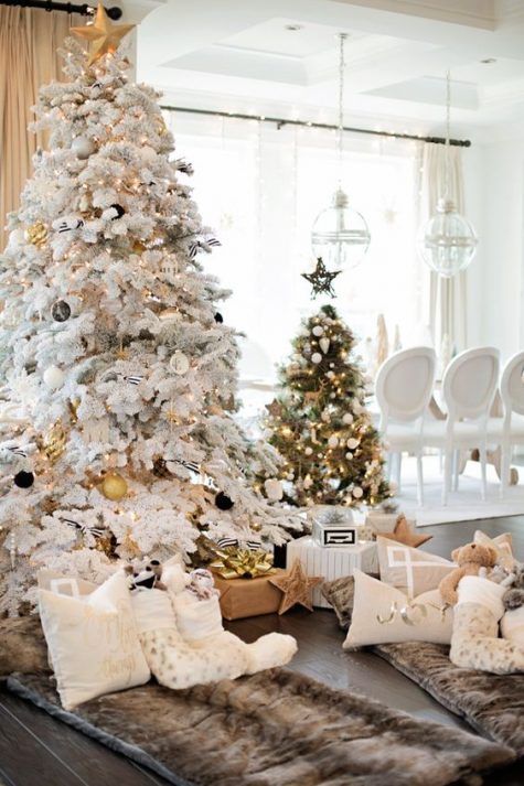 a flocked Christmas tree with black and gold ornaments and a usual one wtih black and white ornaments