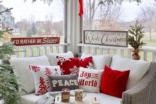 16 a cozy Christmas nook on the porch with red and white pillows, an evergreen garland and signs and candles