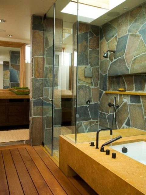 a contemporary bathroom with a touch of rustic chic – a stone wall and stained wooden floors