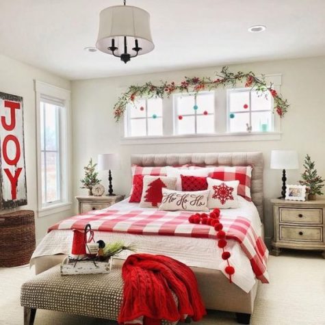 a cozy red and white Christmas bedroom with printed bedding, a knit blanket, a sign and some ornaments