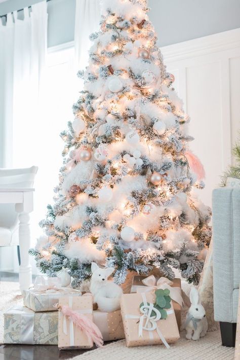 a flocked Christmas tree with white and pastel ornaments, lights and fluffy cotton garlands looks fairy-tale-like