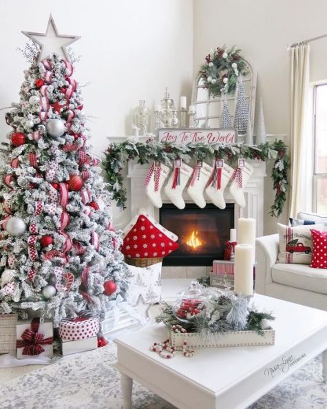 a super cozy and chic farmhouse space done in red and white for Christmas – with a flocked tree, stockings, printed pillows and wreaths