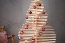27 a wooden Christmas tree with rows of mauve and pink ornaments and lights at the base