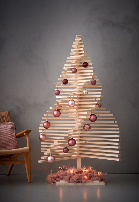 a wooden Christmas tree with rows of mauve and pink ornaments and lights at the base