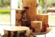 a Christmas centerpiece  of candles wrapped with birch bark, greenery and berries is easy to DIY