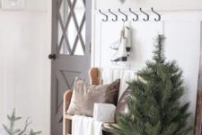a Christmas tree, some velvet pillows, a snowy Christmas wreath with berries for a neutral holiday entryway