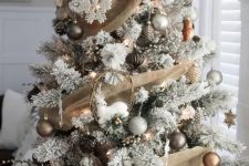 a beautiful winter Christmas tree with burlap ribbons, silver, grey and gold ornaments, deer, white snowflakes and lights