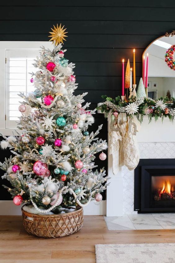 a bright flocked Christmas tree with lights, white, hot pink and neon green ornaments in a basket for a boho space