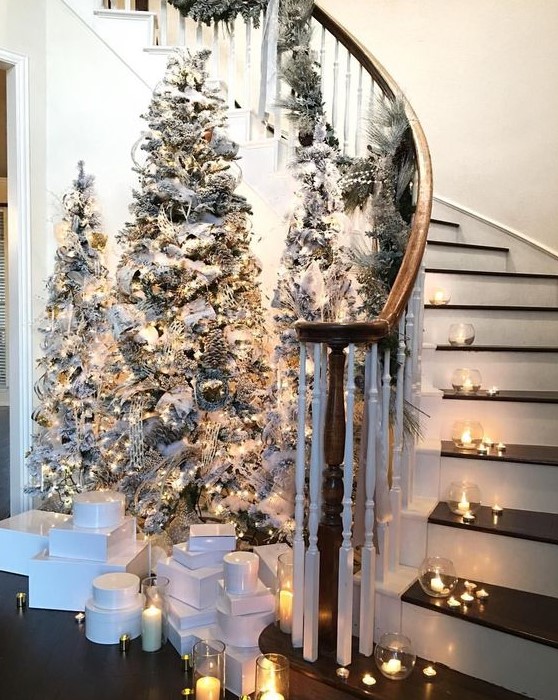 a chic winter fairy tale entryway with tree flocked Christmas trees, lights and neutral ornaments plus candles around