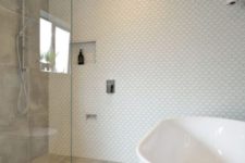 a cool small bathroom with fish scale tiles on the wall, stone grey ones, a tub and pendant lamps