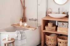 a cozy neutral bathroom with a free-standing tub, a wooden vanity and baskets and branches