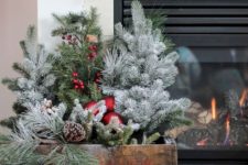 a crate with evergreens, red ornaments, pinecones and berries is a cool Christmas decoration to compose