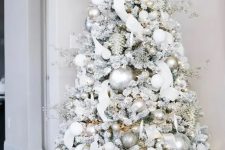 a dreamy flocked Christmas tree with silver and white ornaments, branches, ribbons and lights is an amazing idea