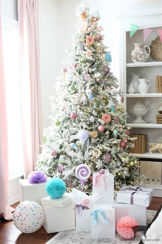 a flocked Christmas tree decorated with pastel ornaments, candy and donut shaped ones, with lights