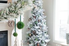 a flocked Christmas tree with gold, brown and green ornaments is a stylish and catchy decor idea for the holidays