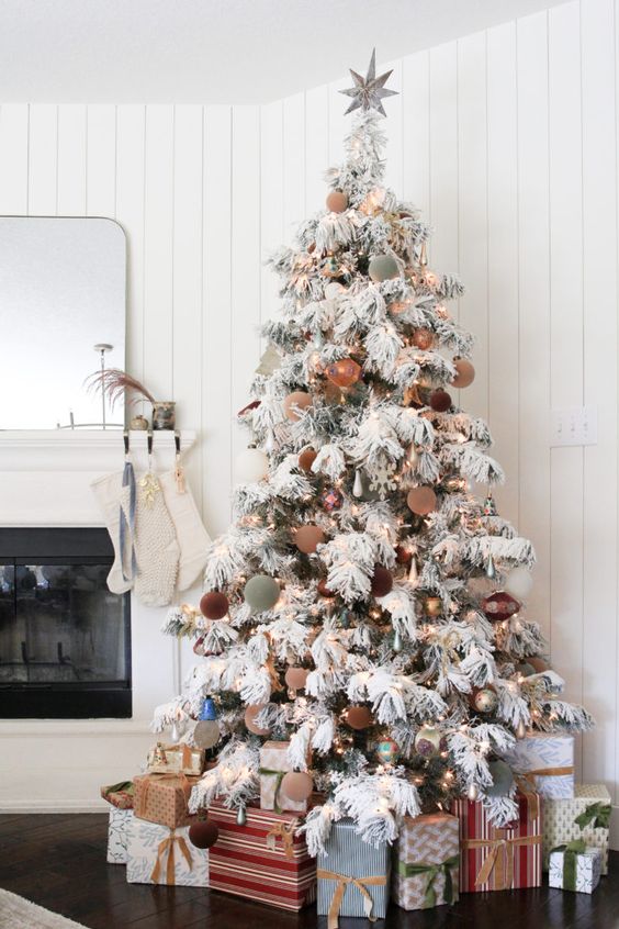 a flocked Christmas tree with lights and muted color ornaments plus a star on top is a cool and catchy idea