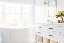 a light-filled neutral bathroom with a shiplap wall, a large vanity and a free-standing tub