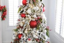 a lovely modern Christmas tree decorated with red and green ornaments, branches and berries, a wooden marquee light topper
