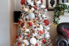 a lovely modern flocked Christmas tree with oversized white, silver and red textural ornaments, smaller ones, plaid ribbons and faux snow plus lights