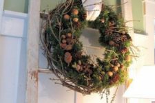 a natural Christmas wreath of greenery, pinecones, nuts, acorns and twigs is a cool decoration for a rustic space