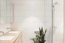 a neutral contemporary bathroom with tiles, a shower space and a double wooden vanity plus potted greenery