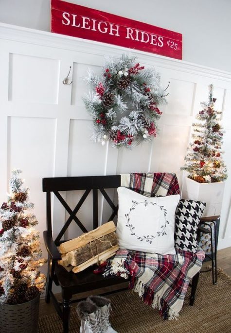 a plaid blanket, firewood, snowy trees with pinecones and a snowy wreath plus a red sign