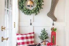 a plaid pillow and a gift box, an evergreen wreath and a stocking with evergreens plus a box with ornaments