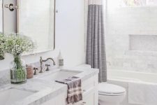 a serene neutral bathroom with hex and marble tiles, a marble vanity countertop, some blooms and a printed curtain