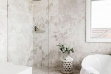 a stylish contemporary bathroom with catchy neutral tiles, a free-standing tub nand a carved wooden table