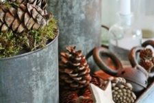 a tray with pinecones, stars, bells, buckets with moss and pinecones for a rustic Christmas