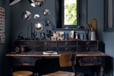 a vintage meets industrial home office with a large vintage wooden desk, metal and wood chairs, vintage lamps and mirrors